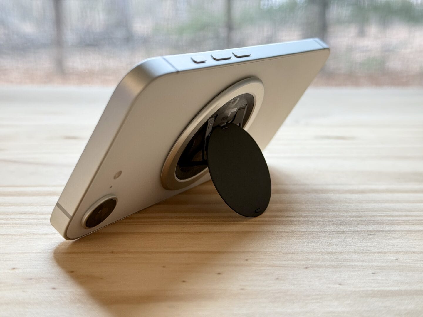iPhone 16e propped up by a MagSafe ring / stand.