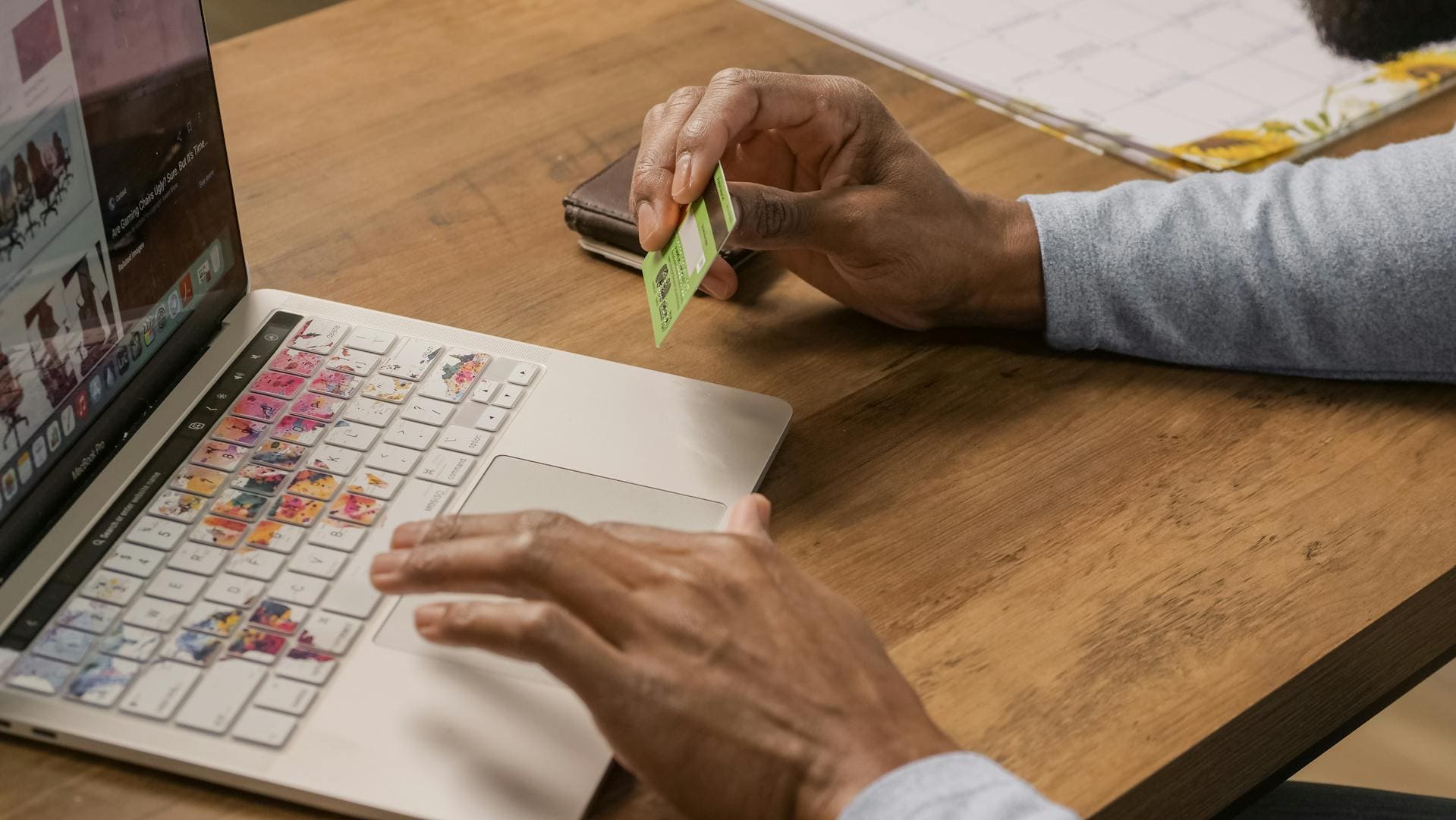 Photo of person holding credit card while using MacBook, used to illustrate a story about how to use Apple reseller reviews to avoid scams