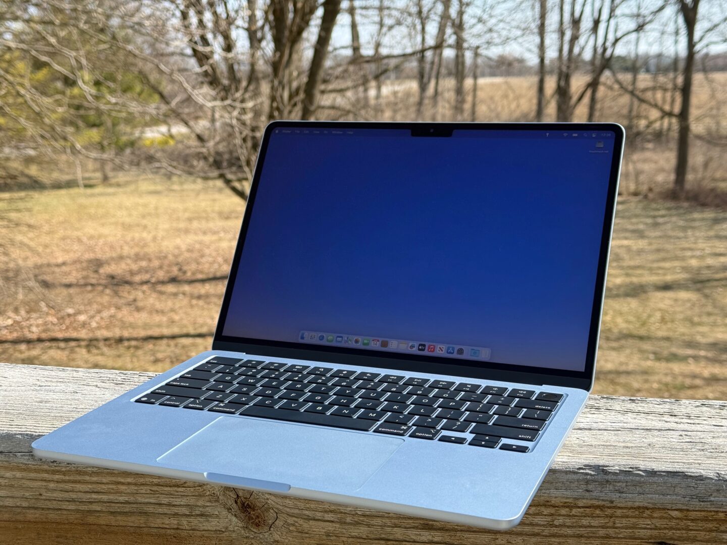 M4 MacBook Air sitting on a porch railing outside in broad daylight